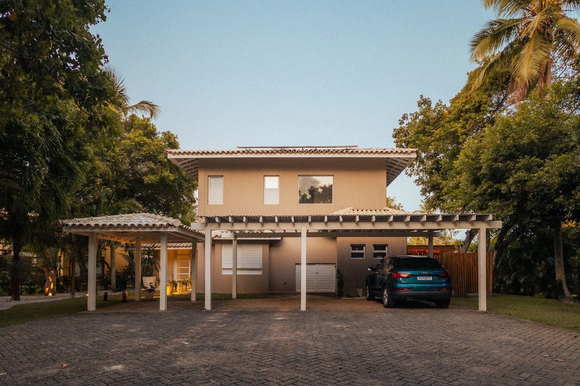 Timber carport roof extending from the front of a large house, showing carport cost factors