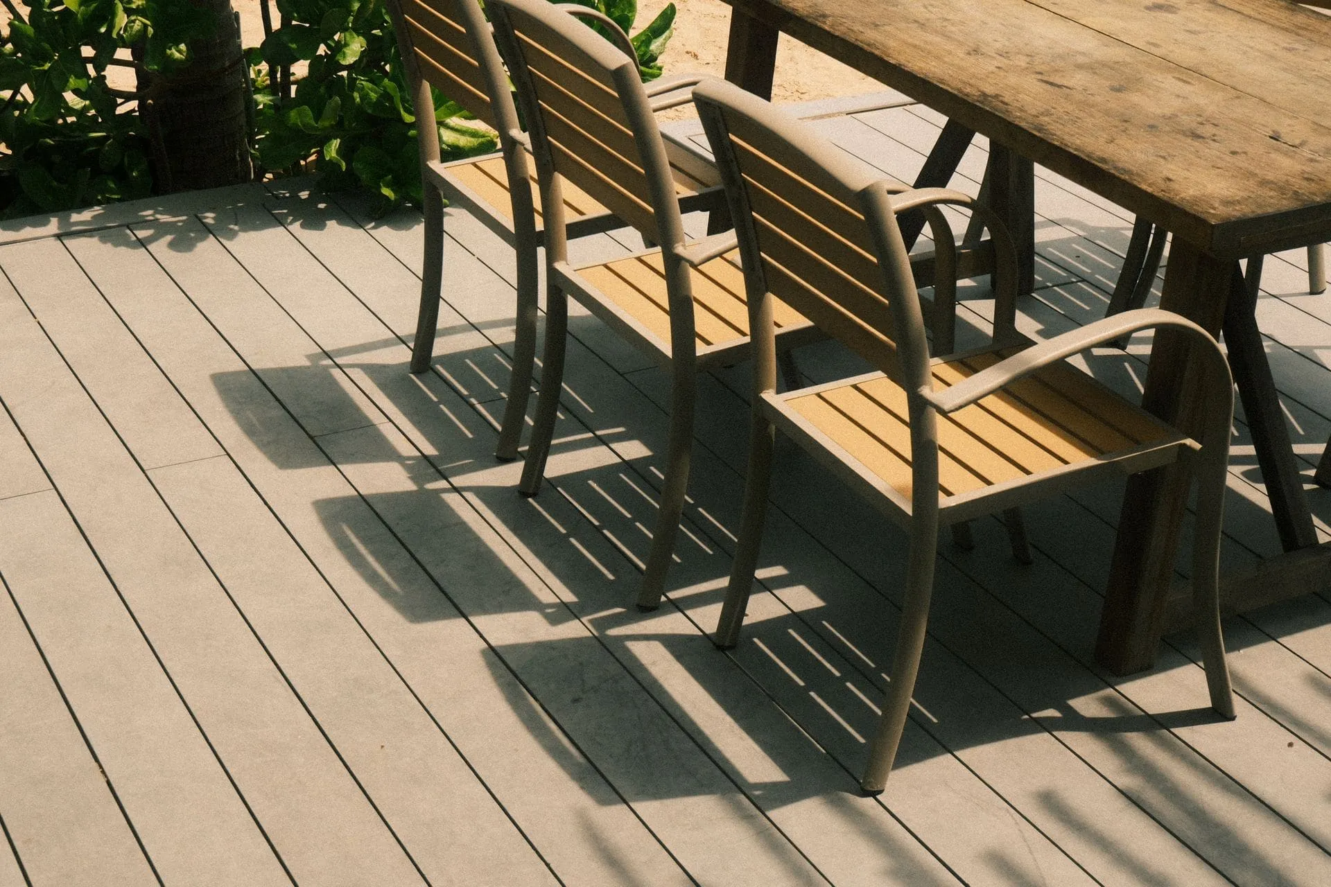 Grey composite decking boards on a sunny deck with outdoor dining chairs and table