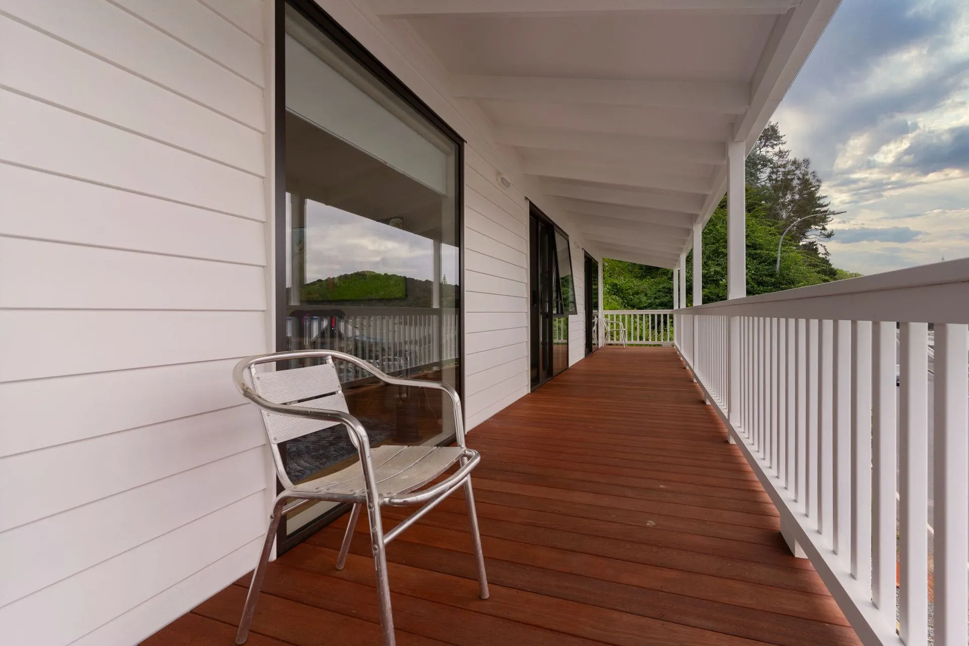 Timber decking on a covered verandah with white balustrade, a factor in decking cost