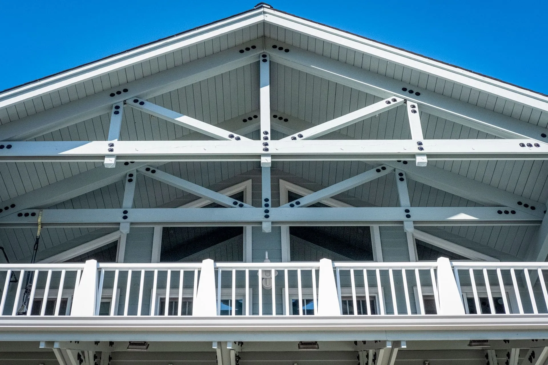 Gable roof patio with white trusses and balustrade, the look of a gable pergola