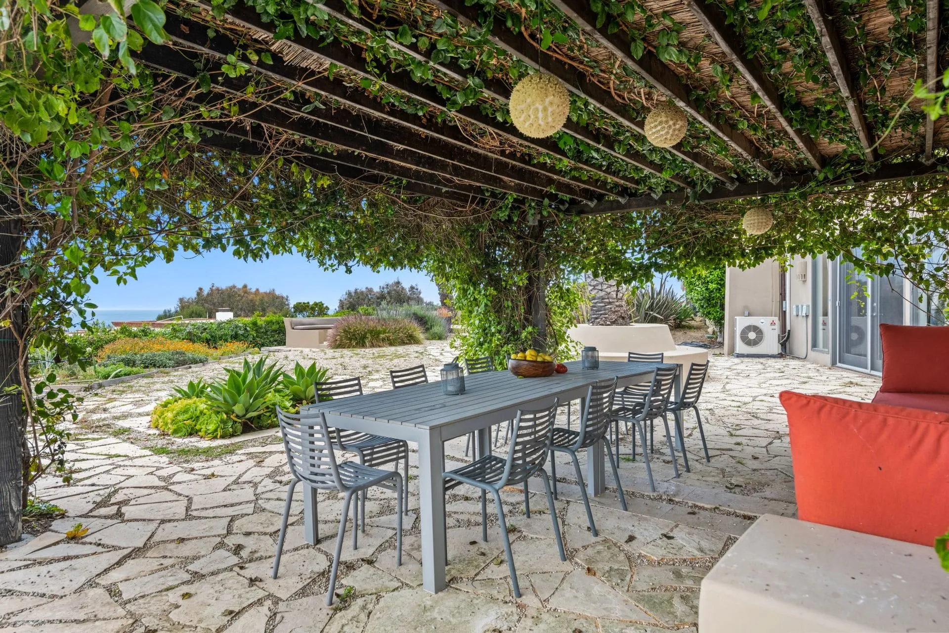 Outdoor entertaining area with a dining table under a vine-covered pergola on paving