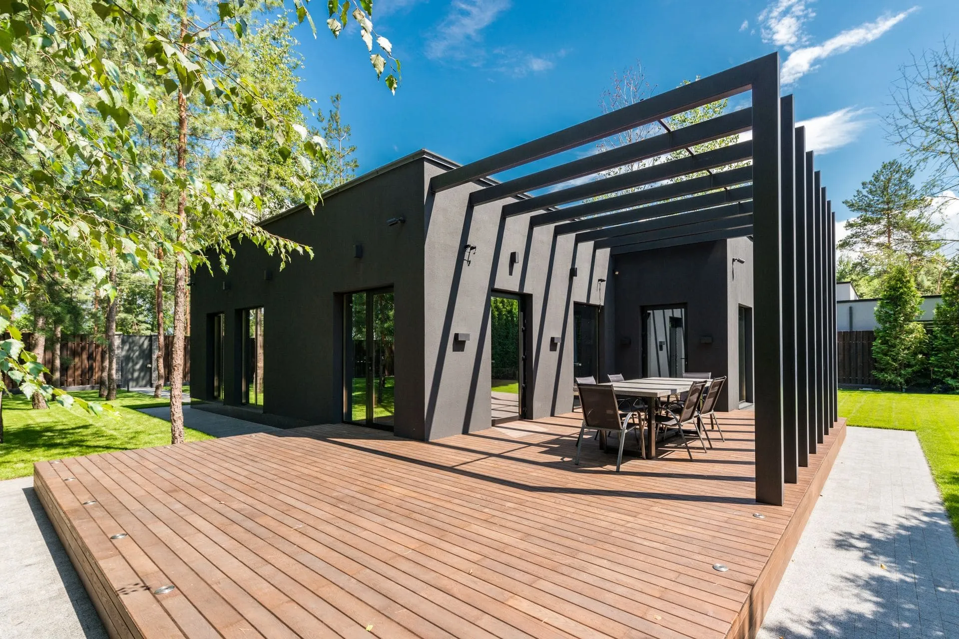 Black steel pergola built on a timber deck beside a modern home