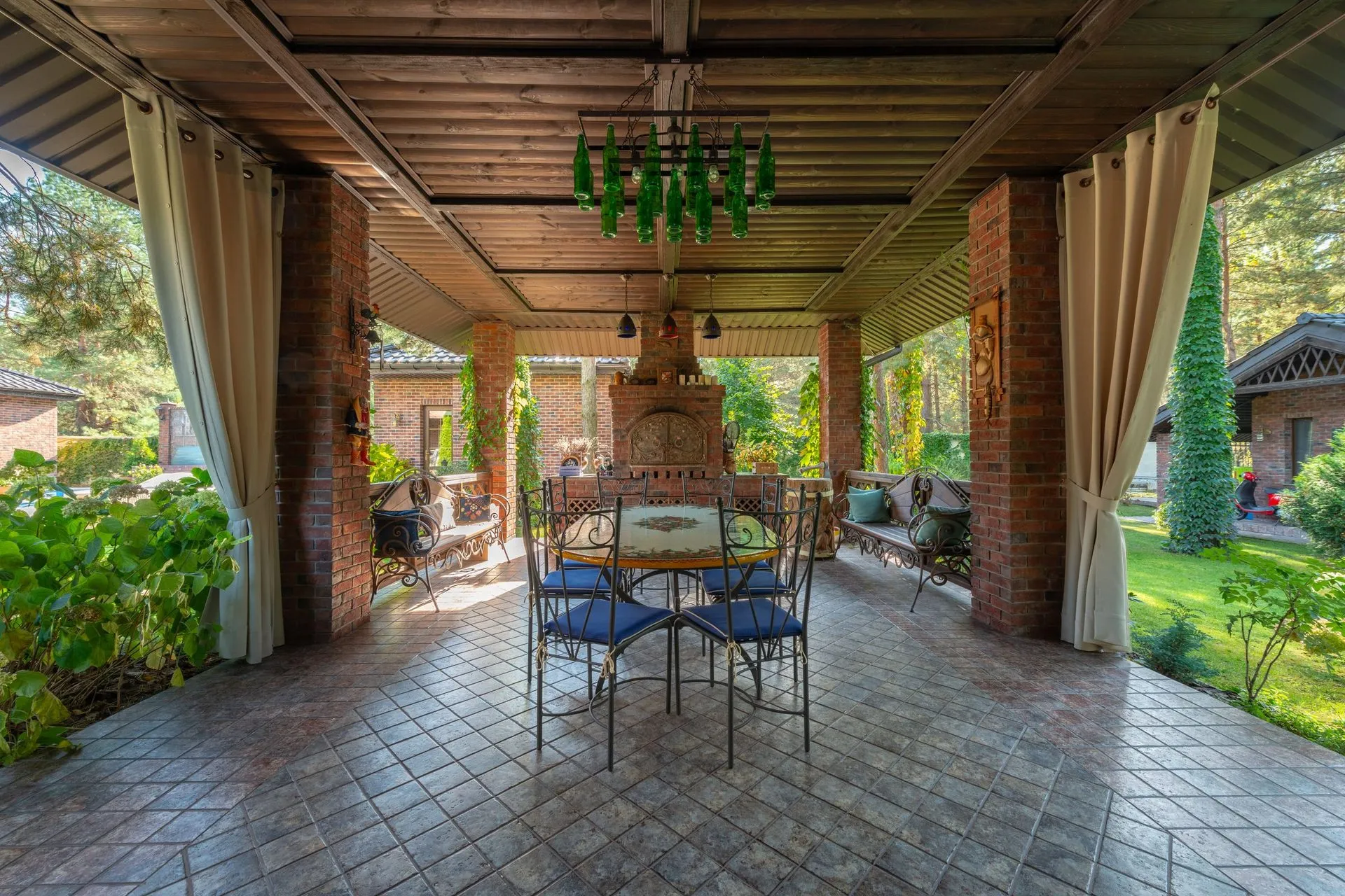 Roofed alfresco area with a tiled floor, dining setting and outdoor curtains