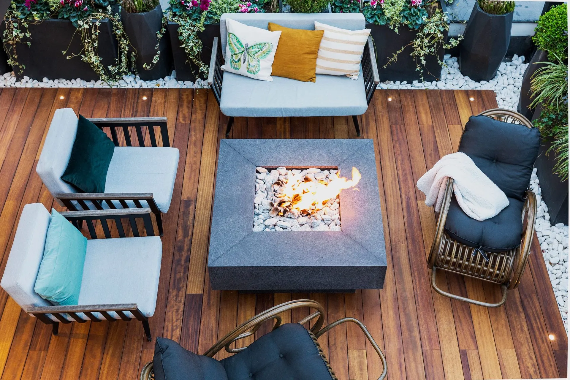 Top-down view of a timber deck with lounge chairs around a fire table