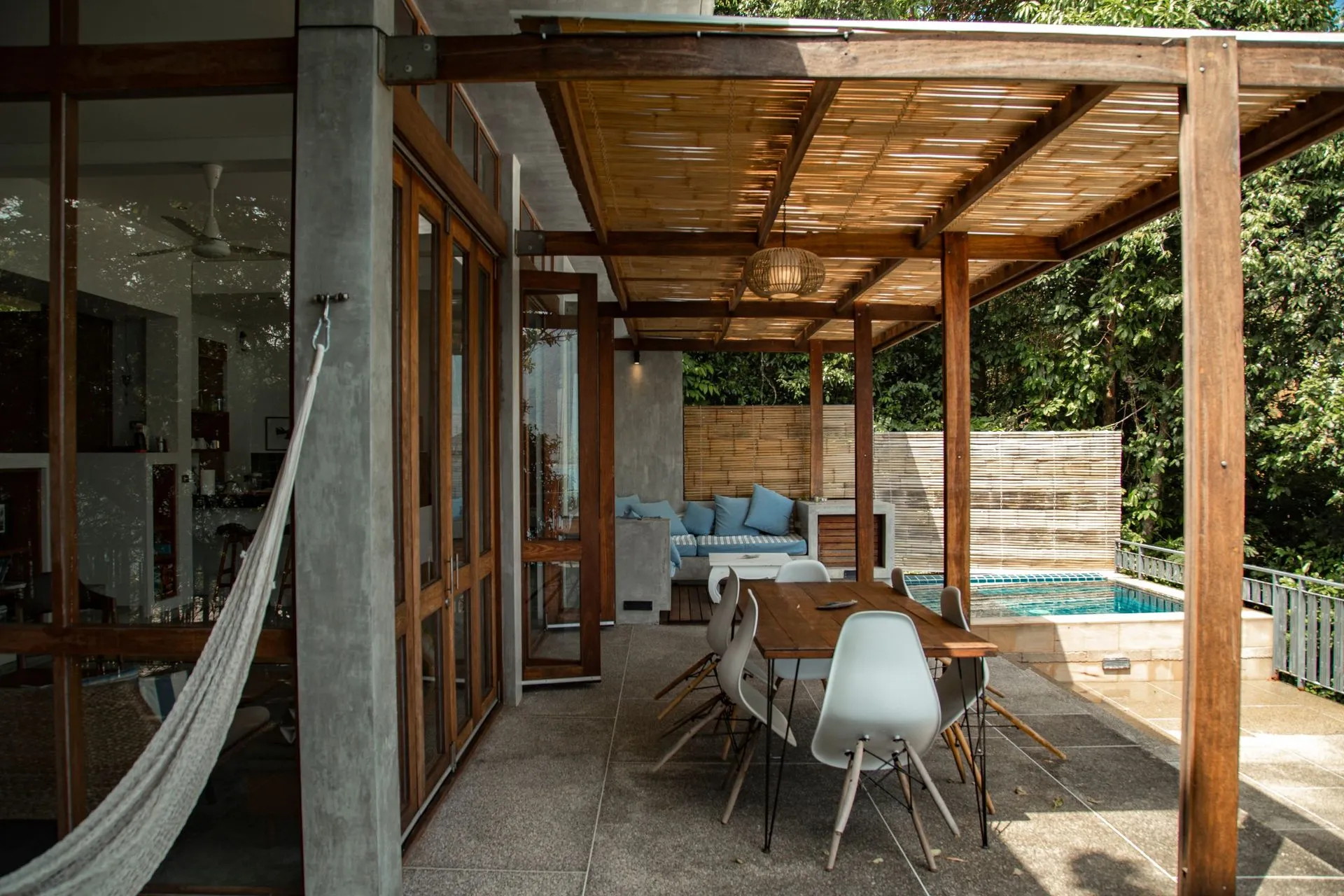 Timber-roofed pergola over an outdoor dining area beside a small pool